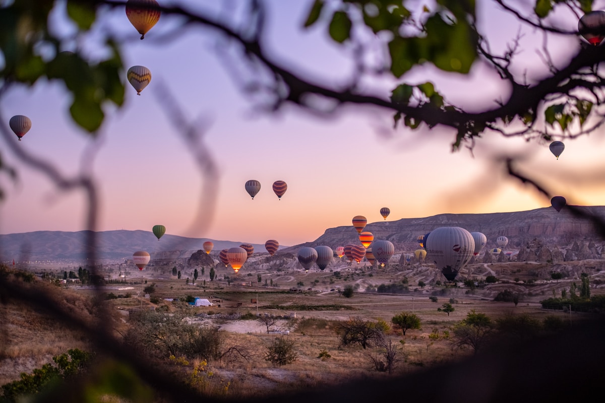 Multiple balloons at different heights drifting over Cappadocia valleys